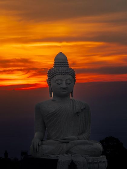A close-up of the Big Buddha statue in Phuket against a fiery sunset. A moment of peace and reflection on Buddha Poornima.