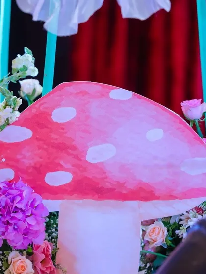 Another one of our handcrafted props, this vibrant pink toadstool, sits among fresh flowers, helping to create a rich and believable enchanted forest floor for guests to admire.