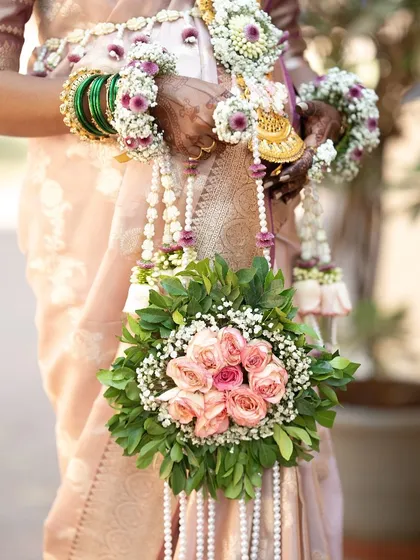 A close-up of a client holding a floral purse made with pink roses and lush greenery. This prop is designed to be held and featured in maternity photos.