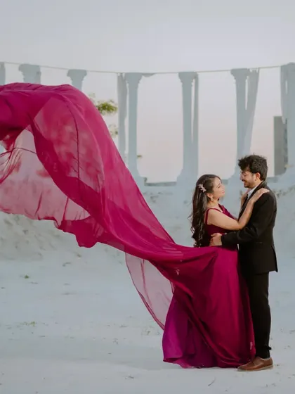 The flowing magenta gown against the white pillars of this set creates a stunning, high-fashion look. This is for couples who want a touch of editorial glamour in their pre-wedding shoot.