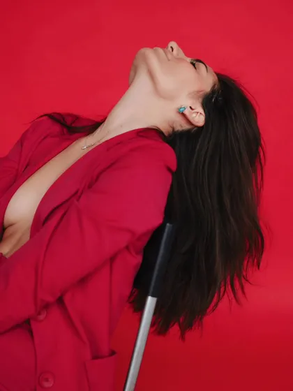 A moment of pure abandon and confidence. This shot captures a powerful emotion, with the model leaning back against a vibrant red background.