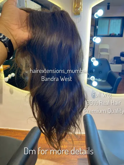 A close-up of a full wig held up to show its construction and hair quality. This piece is made in our Bandra West studio with 100% real, premium quality hair.