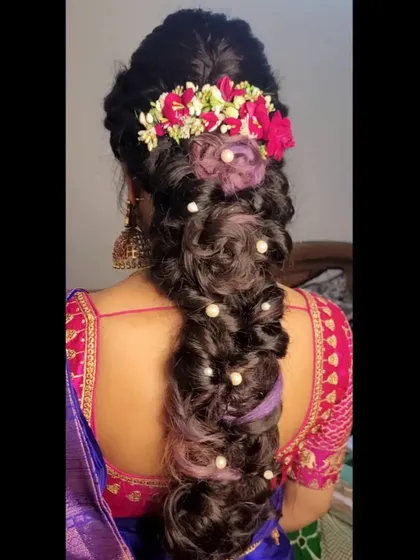 The final result of a contemporary bridal hairstyle. This textured braid is a work of art, combining fresh flowers, pearl accents, and colored hair for a bold and modern statement.