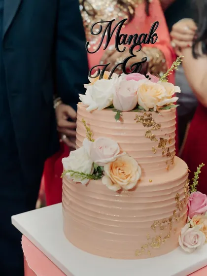 Celebrating love with this elegant two-tier anniversary cake. The combination of soft pink buttercream, delicate gold leaf, and fresh roses creates a timeless and romantic look.