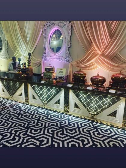 An elegant buffet station with geometric-patterned counters and dramatic draping in the background. The setup is designed to be both functional and a part of the event's decor.