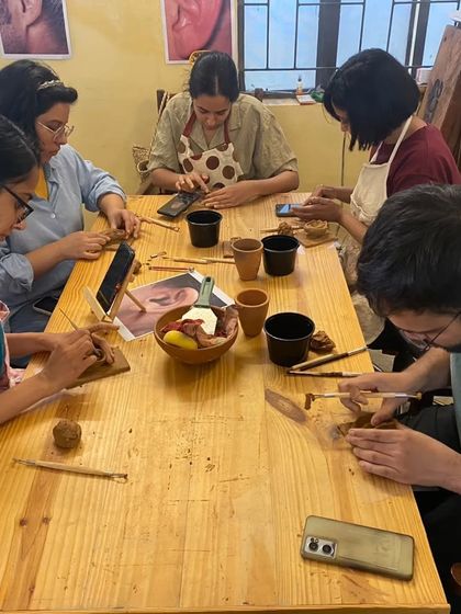 A group of participants fully engaged in the ear sculpting workshop. The communal table setup fosters a collaborative and supportive atmosphere where everyone can learn together.