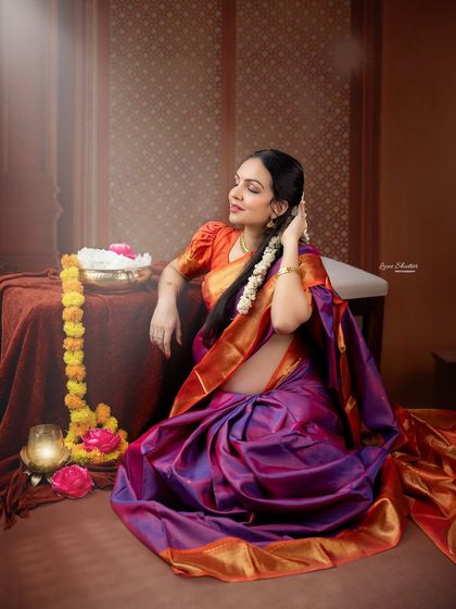 Lost in a daydream. This candid-style portrait captures a beautiful, unposed moment, highlighting the intricate details of the saree and the jasmine flowers in her hair.