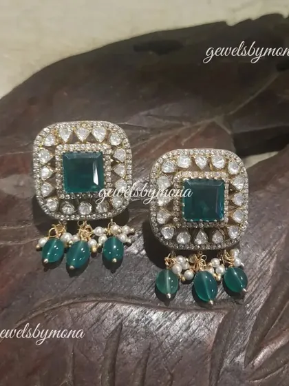 These square-shaped polki studs with green bead drops are a modern take on traditional design. They are perfect for adding a touch of sparkle and color to any outfit.