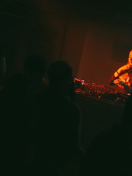 A more intimate view of the DJ booth, with the crowd silhouetted in the foreground. It's about creating a shared space.