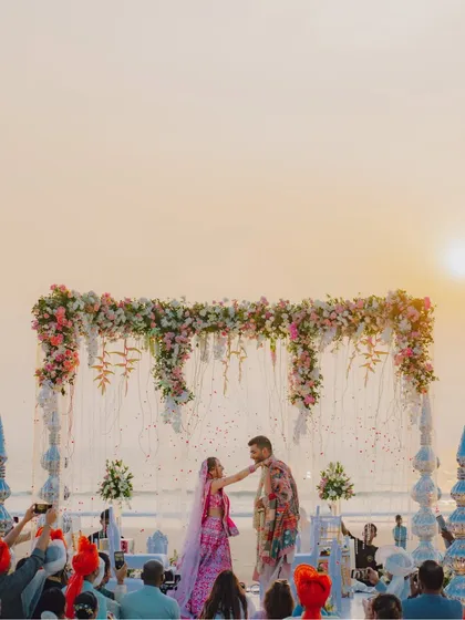 A sunset Varmala ceremony on a Goa beach. The golden light and the ocean backdrop make for an incredibly romantic setting, and we ensure we capture this magical atmosphere in our destination wedding photography.