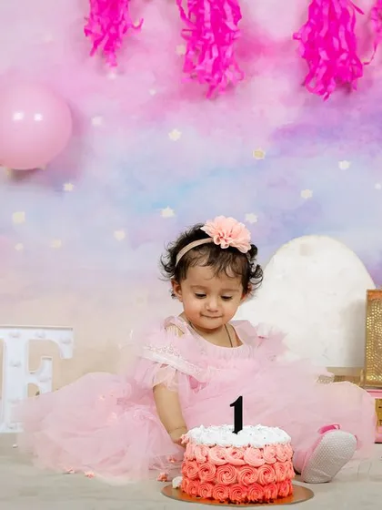 The birthday girl curiously touching her first birthday cake. This shot captures the beginning of a fun and memorable cake smash experience.