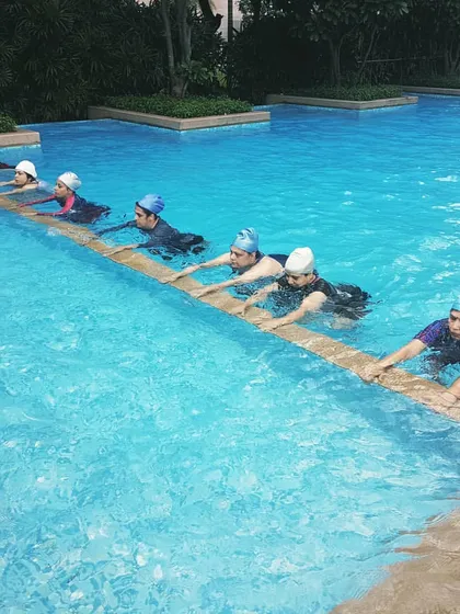 My women's batch works on leg exercises at the pool's edge. This movement helps build lower body strength and endurance with the water providing gentle resistance.