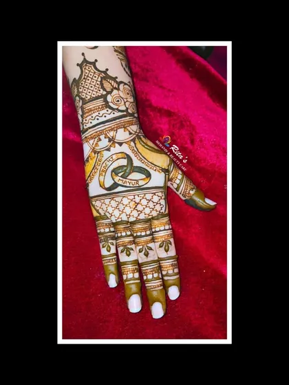 The other hand features interlocking engagement rings, a classic symbol for a 'sagaikimehendi'.