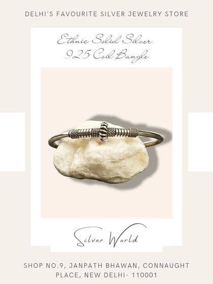 An ethnic solid silver coil bangle. The coiled design in the center adds a unique, handcrafted touch to this open-ended bangle.
