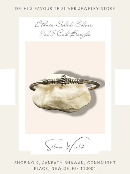 An ethnic solid silver coil bangle. The coiled design in the center adds a unique, handcrafted touch to this open-ended bangle.