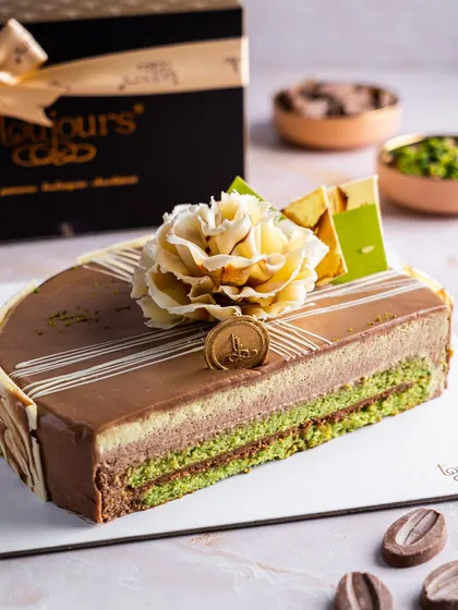 Our Chocolate Pistachio Entremet, a layered loaf cake with a beautiful marbled chocolate flower on top. The distinct layers of pistachio sponge and chocolate mousse are visible, offering a rich and nutty flavour profile.