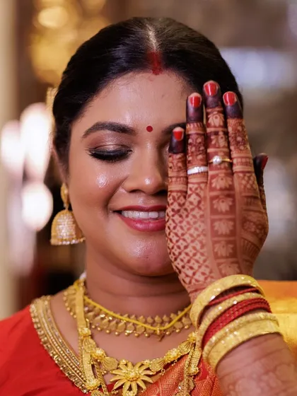 A close up showcasing the detailed eye makeup and flawless skin for the South Indian bride. The look is paired with her intricate henna design and traditional gold jewelry.