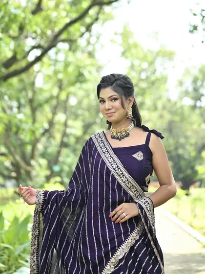 A smiling model in the purple leheriya lehenga, showcasing the outfit's elegant simplicity and beautiful color.