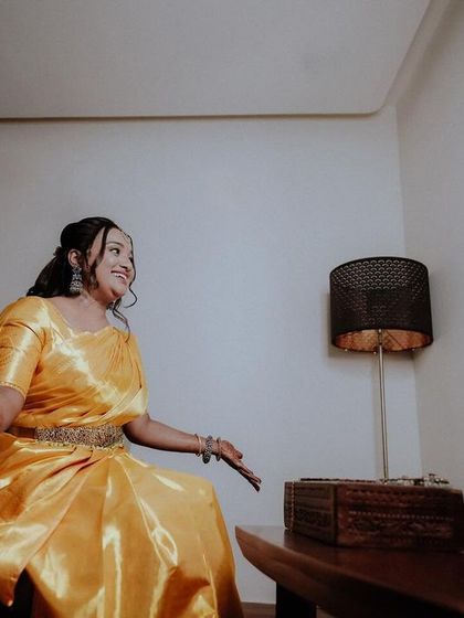 The bride, dressed in a stunning yellow saree, caught in a moment of happy conversation during her engagement.