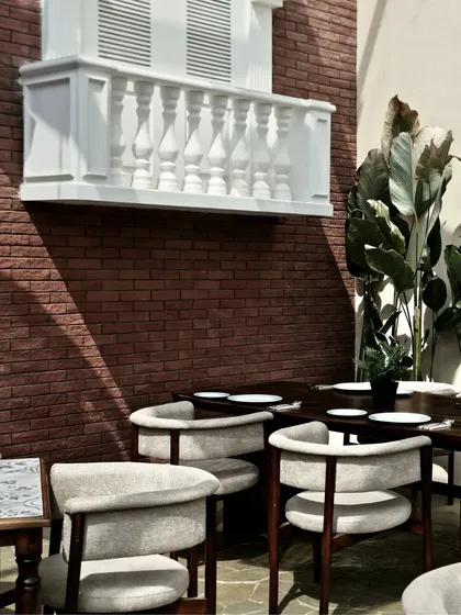 A close-up of the faux balcony against the exposed brick wall. This detail shows the craftsmanship of the balustrade and the interplay of light and shadow, adding depth and a sense of history to the interior.