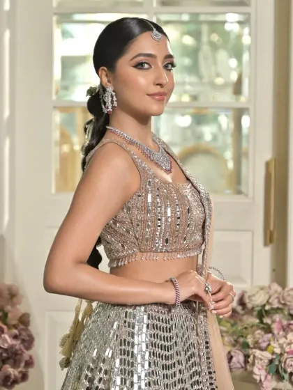 This shot shows the overall look, where the modern bubble braid complements a stunning mirror-work lehenga. The hairstyle adds a contemporary edge to the bridal ensemble.