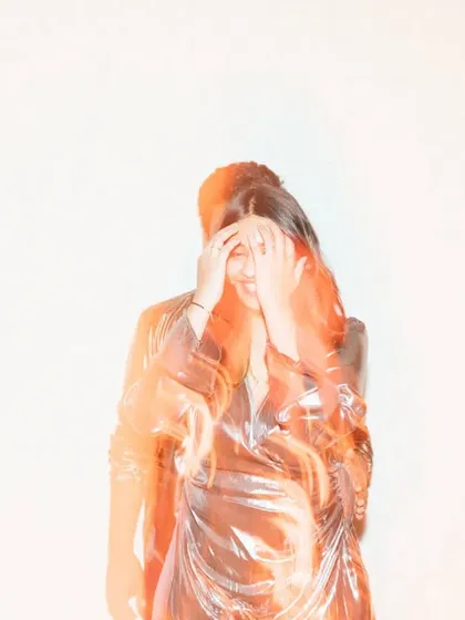 An artistic and emotive portrait using motion and a warm light overlay. The bride's face is partially hidden by her hands, creating a sense of mystery and introspection in this abstract shot.