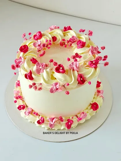 The full view of the effortlessly beautiful Gypso cake, with its soft swirls of cream and tiny pink flowers.