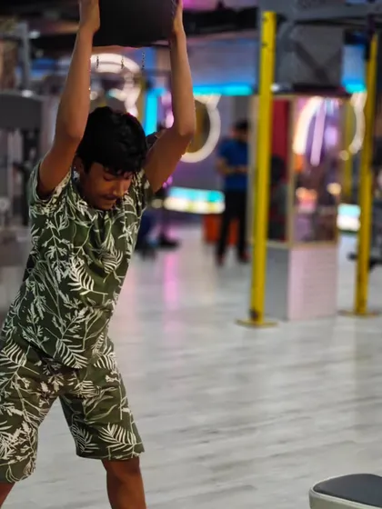 A member performing a plate ground-to-overhead lift. This is a full-body functional movement that builds explosive power and strength.
