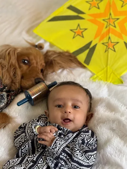 A happy baby and a happy dog celebrating their first Makar Sankranti together.