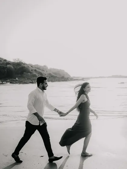 Another dynamic shot of the couple walking along the beach. The black and white edit emphasizes the movement and the joy in their interaction.