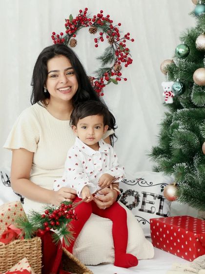 A lovely mother-daughter Christmas portrait. The bright red tights and festive decor make this a cheerful and heartwarming photo.