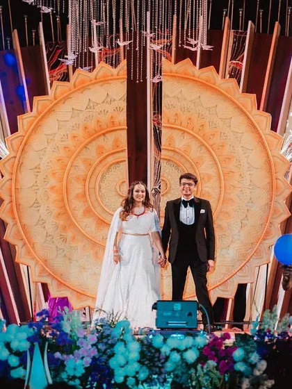 The couple makes their grand entry, framed by a stunning custom backdrop and surrounded by dancers and cold-spark pyrotechnics.