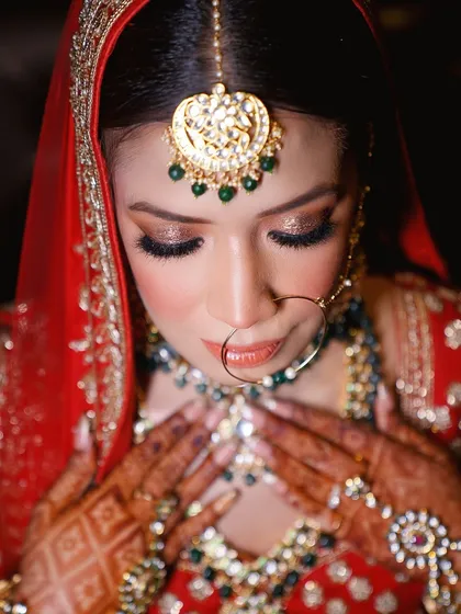 A downward glance, capturing a moment of quiet elegance. This portrait focuses on the bride's stunning jewelry and intricate makeup.