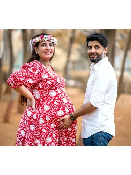 A classic couple maternity pose. The father-to-be places a hand on the baby bump, connecting with his partner and their unborn child in a simple, loving gesture.