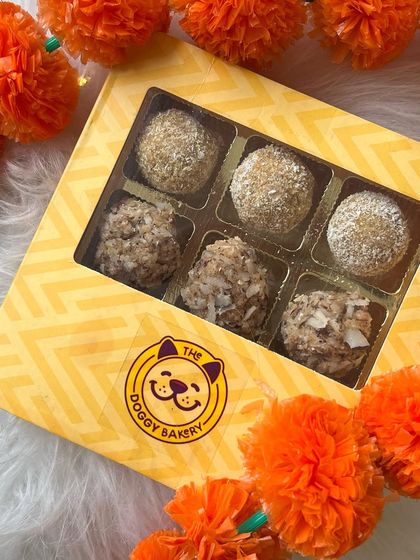 A close-up of our festive ladoo box, surrounded by marigolds. Each ladoo is handcrafted with love and healthy ingredients, perfect for spoiling your pup.
