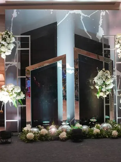 A modern and edgy photo booth, created with angled mirrors and clean white floral arrangements, offering a unique and artistic spot for guest photos.