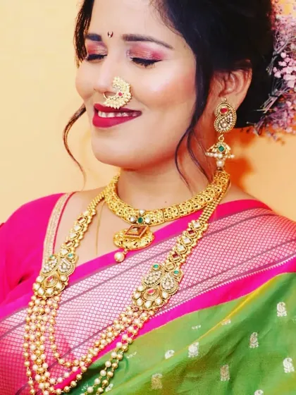 A beautiful client looking radiant in her Maharashtrian attire. She is wearing a layered pearl and gold necklace set that adds grace and elegance.