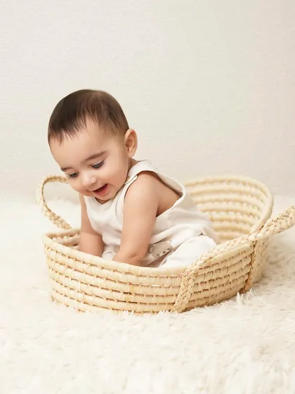 A moment of discovery and play as the baby looks down into the basket with a happy smile. These candid shots are full of charm.