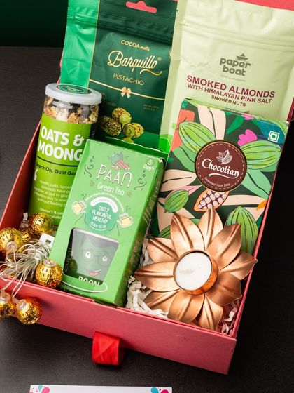 A healthy and refreshing take on Diwali gifting, this hamper is packed with green-themed goodies. It includes pistachio barquillo, smoked almonds, oats and moong, paan-flavored green tea, and a beautiful copper flower diya for a touch of festive light.