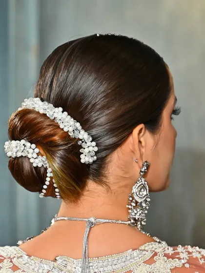 A three-quarter view of the pearl-adorned bun, showcasing its intricate design and clean finish. This is a classic style elevated with a modern accessory.