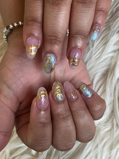 A chic design featuring a sheer base with gold foil details and glitter accents on almond-shaped nails.