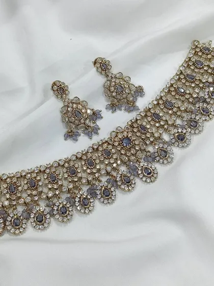 A unique and modern choice, this choker set features grey stones for a contemporary, chic look. It pairs beautifully with silver-threaded outfits or pastel lehengas.