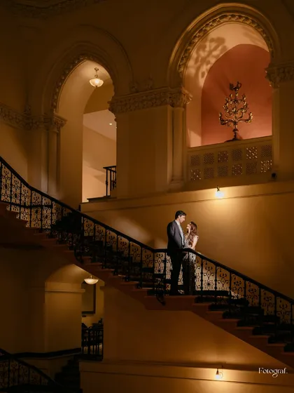I love playing with light and architecture to create portraits that feel like art. Here, the grandeur of the staircase and the soft lighting frame the couple in a classic, romantic moment.