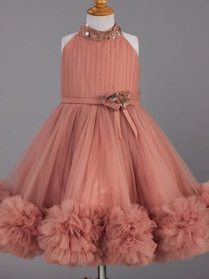 This dusty rose dress features a pleated bodice and a unique pom pom hemline.