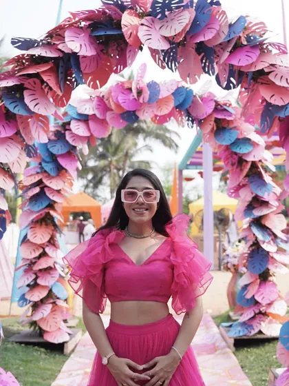 A fun and quirky pose in front of a colorful paper-leaf arch at a destination wedding in Goa.