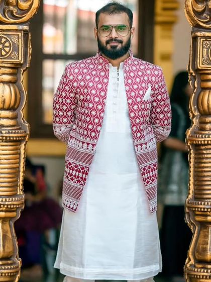 A client looking dapper in the red and white embroidered open Jodhpuri, captured in a beautiful architectural setting.