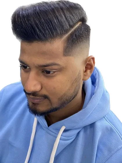 A still shot of a perfectly executed fade and beard combination. The hard part line and the clean cheek line demonstrate the precision that goes into every cut.