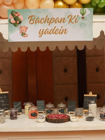 The signage for the 'Bachpan Ki Yaadein' candy cart, featuring a cute teddy bear and hot air balloon graphic to match the baby shower theme.