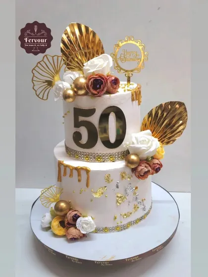 Celebrating 50 golden years together with this grand two-tier chocolate mousse cake. It's decorated with gold drip, gold leaf, and beautiful flowers, perfectly capturing the essence of a golden anniversary.