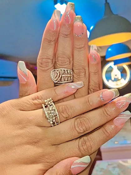 A glamorous set of long, coffin-shaped nails with a nude base, accented with wavy silver glitter lines. This design is elegant with a touch of sparkle.